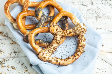 Taze ev yapımı yumuşak krakerler. Siyah arka planda tohumları olan farklı pişmiş simit türleri.
