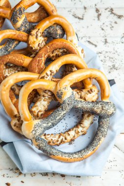 Taze ev yapımı yumuşak krakerler. Siyah arka planda tohumları olan farklı pişmiş simit türleri.