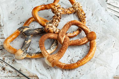 Taze ev yapımı yumuşak krakerler. Siyah arka planda tohumları olan farklı pişmiş simit türleri.