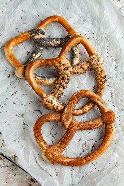 Taze ev yapımı yumuşak krakerler. Siyah arka planda tohumları olan farklı pişmiş simit türleri.