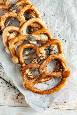 Taze ev yapımı yumuşak krakerler. Siyah arka planda tohumları olan farklı pişmiş simit türleri.