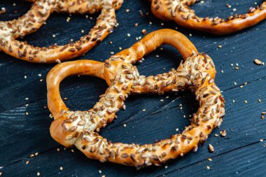 Taze ev yapımı yumuşak krakerler. Siyah arka planda tohumları olan farklı pişmiş simit türleri..