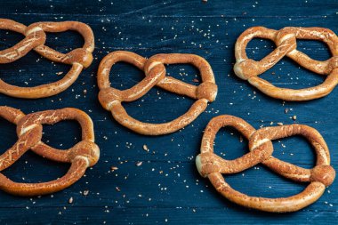 Taze ev yapımı yumuşak krakerler. Siyah arka planda tohumları olan farklı pişmiş simit türleri..