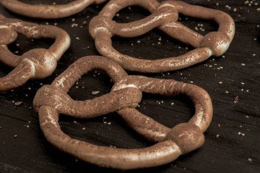 Taze ev yapımı yumuşak krakerler. Siyah arka planda tohumları olan farklı pişmiş simit türleri..