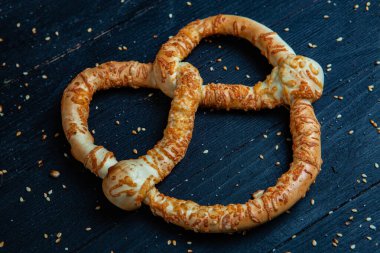 Taze ev yapımı yumuşak krakerler. Siyah arka planda tohumları olan farklı pişmiş simit türleri..