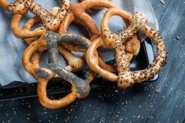 Taze ev yapımı yumuşak krakerler. Siyah arka planda tohumları olan farklı pişmiş simit türleri..