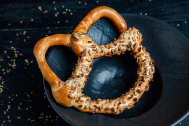 Taze ev yapımı yumuşak krakerler. Siyah arka planda tohumları olan farklı pişmiş simit türleri..