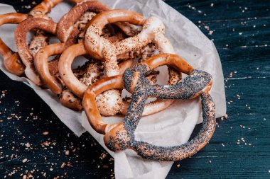 Taze ev yapımı yumuşak krakerler. Siyah arka planda tohumları olan farklı pişmiş simit türleri..