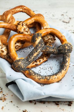Taze ev yapımı yumuşak krakerler. Siyah arka planda tohumları olan farklı pişmiş simit türleri..