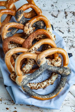 Taze ev yapımı yumuşak krakerler. Siyah arka planda tohumları olan farklı pişmiş simit türleri..