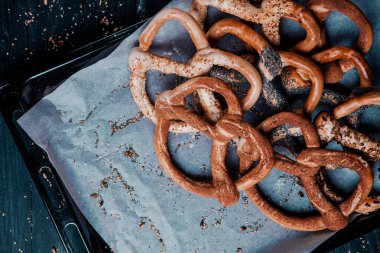 Taze ev yapımı yumuşak krakerler. Siyah arka planda tohumları olan farklı pişmiş simit türleri..