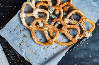 Taze ev yapımı yumuşak krakerler. Siyah arka planda tohumları olan farklı pişmiş simit türleri..