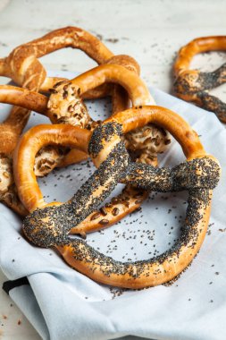 Taze ev yapımı yumuşak krakerler. Siyah arka planda tohumları olan farklı pişmiş simit türleri..