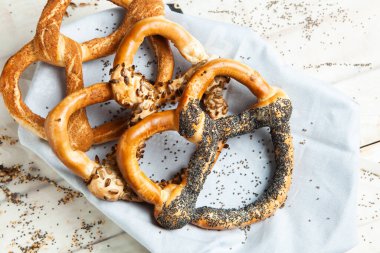 Taze ev yapımı yumuşak krakerler. Siyah arka planda tohumları olan farklı pişmiş simit türleri..