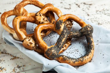 Taze ev yapımı yumuşak krakerler. Siyah arka planda tohumları olan farklı pişmiş simit türleri..