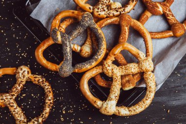 Taze ev yapımı yumuşak krakerler. Siyah arka planda tohumları olan farklı pişmiş simit türleri..