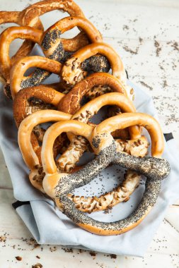 Taze ev yapımı yumuşak krakerler. Siyah arka planda tohumları olan farklı pişmiş simit türleri..