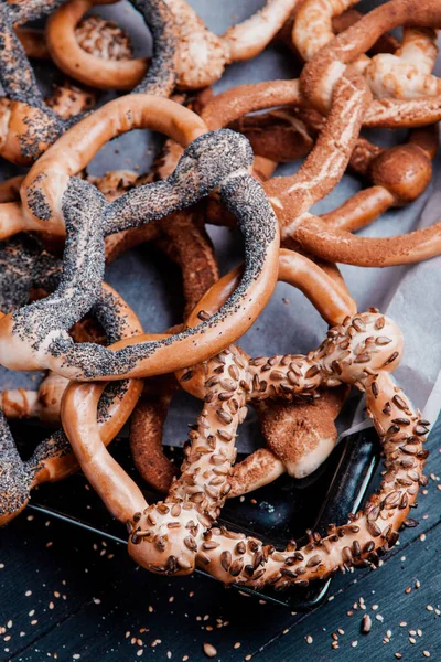 Taze ev yapımı yumuşak krakerler. Siyah arka planda tohumları olan farklı pişmiş simit türleri..