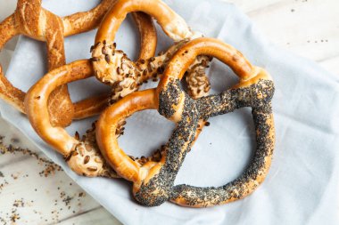Taze ev yapımı yumuşak krakerler. Siyah arka planda tohumları olan farklı pişmiş simit türleri..