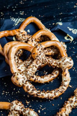 Taze ev yapımı yumuşak krakerler. Siyah arka planda tohumları olan farklı pişmiş simit türleri..