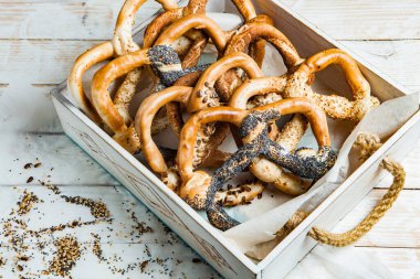 Taze ev yapımı yumuşak krakerler. Siyah arka planda tohumları olan farklı pişmiş simit türleri..