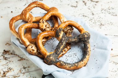 Taze ev yapımı yumuşak krakerler. Siyah arka planda tohumları olan farklı pişmiş simit türleri..