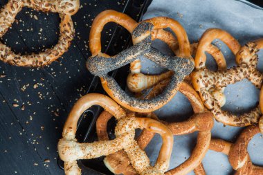 Taze ev yapımı yumuşak krakerler. Siyah arka planda tohumları olan farklı pişmiş simit türleri..