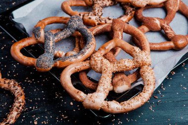 Taze ev yapımı yumuşak krakerler. Siyah arka planda tohumları olan farklı pişmiş simit türleri..