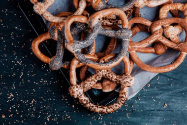 Taze ev yapımı yumuşak krakerler. Siyah arka planda tohumları olan farklı pişmiş simit türleri..