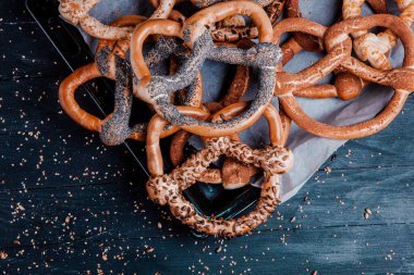 Taze ev yapımı yumuşak krakerler. Siyah arka planda tohumları olan farklı pişmiş simit türleri..