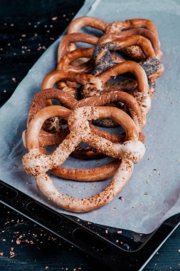 Taze ev yapımı yumuşak krakerler. Siyah arka planda tohumları olan farklı pişmiş simit türleri..