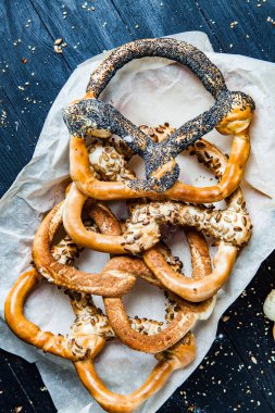 Taze ev yapımı yumuşak krakerler. Siyah arka planda tohumları olan farklı pişmiş simit türleri..