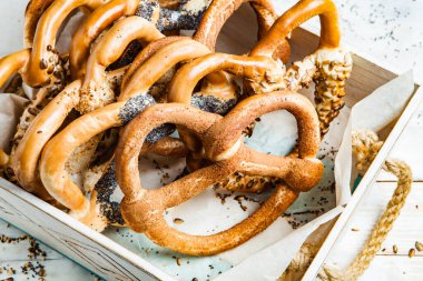 Taze ev yapımı yumuşak krakerler. Siyah arka planda tohumları olan farklı pişmiş simit türleri..