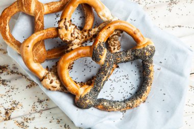 Taze ev yapımı yumuşak krakerler. Siyah arka planda tohumları olan farklı pişmiş simit türleri..