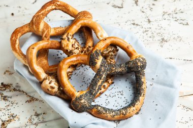 Taze ev yapımı yumuşak krakerler. Siyah arka planda tohumları olan farklı pişmiş simit türleri..