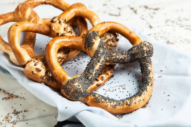 Taze ev yapımı yumuşak krakerler. Siyah arka planda tohumları olan farklı pişmiş simit türleri..