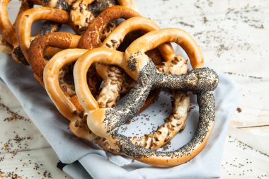 Taze ev yapımı yumuşak krakerler. Siyah arka planda tohumları olan farklı pişmiş simit türleri..