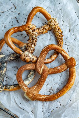 Taze ev yapımı yumuşak krakerler. Siyah arka planda tohumları olan farklı pişmiş simit türleri..