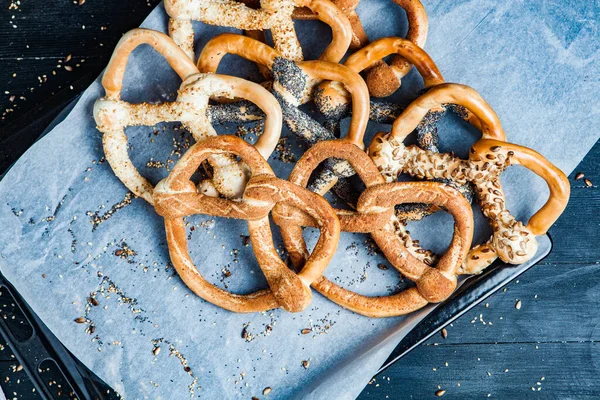 Taze ev yapımı yumuşak krakerler. Siyah arka planda tohumları olan farklı pişmiş simit türleri..