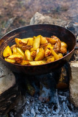 Dışarıda ateşte kızartma tavasında ev yapımı çıtır patates. Doğada piknik yapmak ve yemek yapmak..