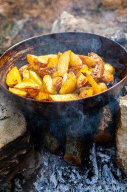 Dışarıda ateşte kızartma tavasında ev yapımı çıtır patates. Doğada piknik yapmak ve yemek yapmak..