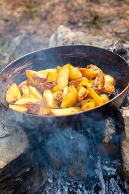 Dışarıda ateşte kızartma tavasında ev yapımı çıtır patates. Doğada piknik yapmak ve yemek yapmak..