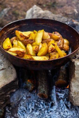 Dışarıda ateşte kızartma tavasında ev yapımı çıtır patates. Doğada piknik yapmak ve yemek yapmak..