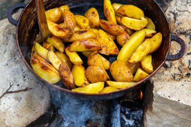 Dışarıda ateşte kızartma tavasında ev yapımı çıtır patates. Doğada piknik yapmak ve yemek yapmak..