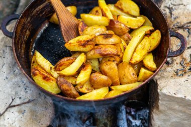 Dışarıda ateşte kızartma tavasında ev yapımı çıtır patates. Doğada piknik yapmak ve yemek yapmak..