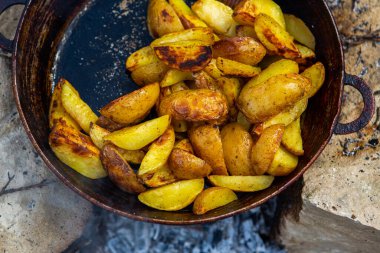 Dışarıda ateşte kızartma tavasında ev yapımı çıtır patates. Doğada piknik yapmak ve yemek yapmak..