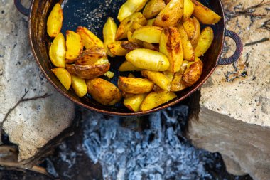 Dışarıda ateşte kızartma tavasında ev yapımı çıtır patates. Doğada piknik yapmak ve yemek yapmak..