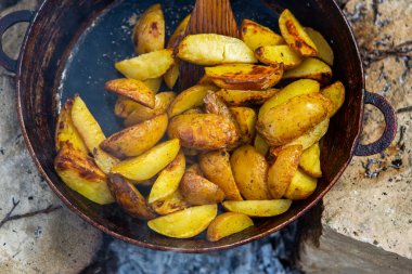 Dışarıda ateşte kızartma tavasında ev yapımı çıtır patates. Doğada piknik yapmak ve yemek yapmak..