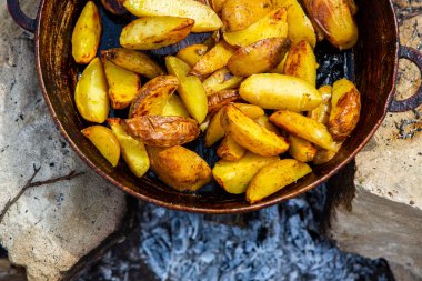 Dışarıda ateşte kızartma tavasında ev yapımı çıtır patates. Doğada piknik yapmak ve yemek yapmak..