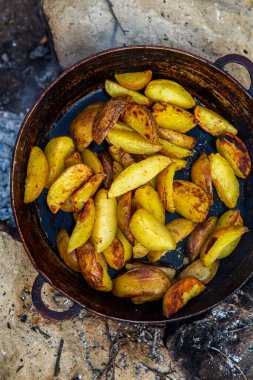 Dışarıda ateşte kızartma tavasında ev yapımı çıtır patates. Doğada piknik yapmak ve yemek yapmak..